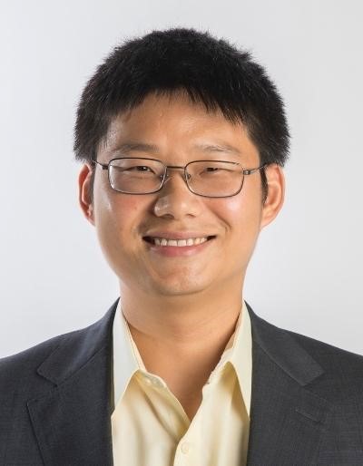 A person wearing glasses and a suit Description automatically generated